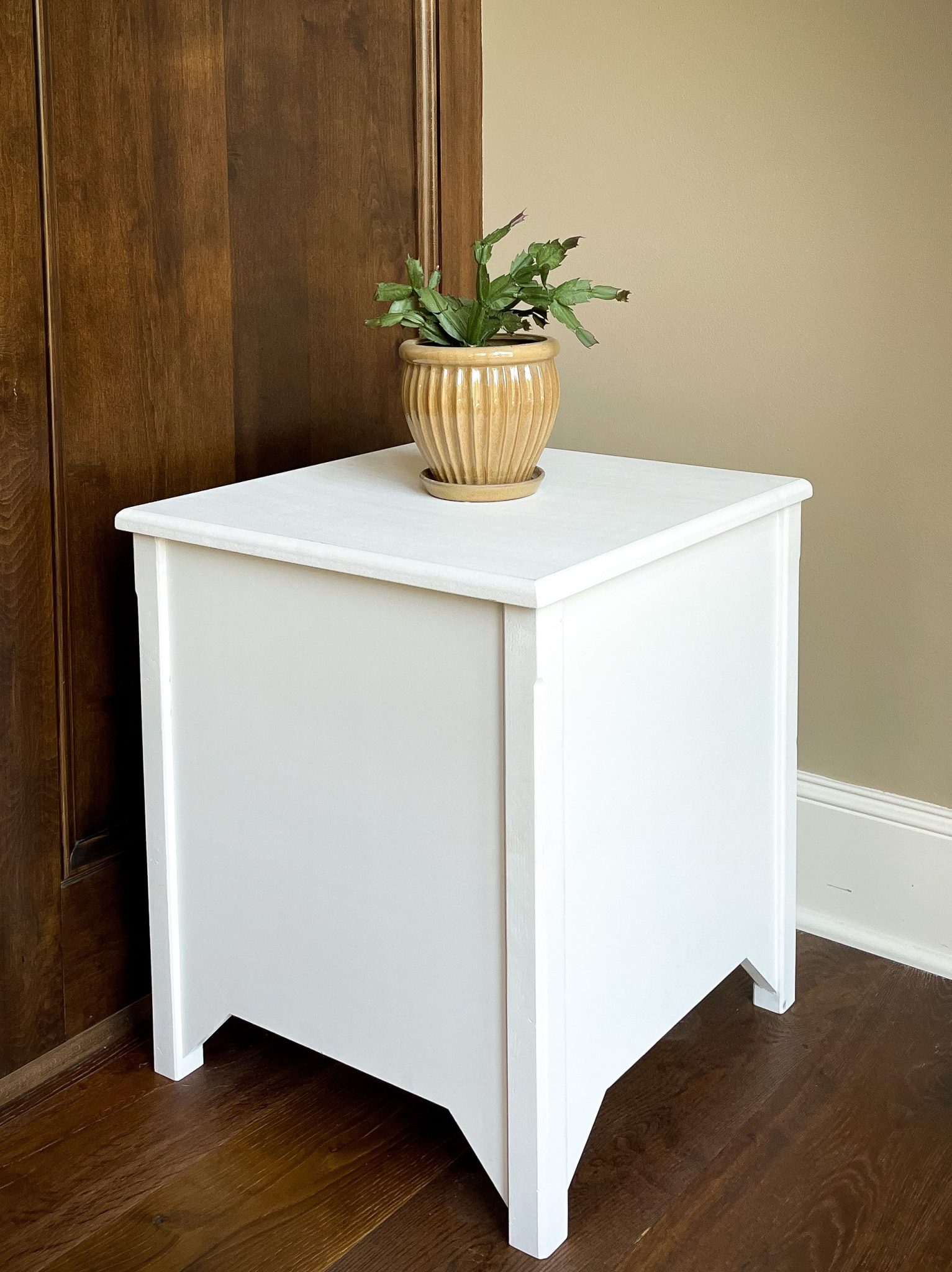 A sleek white painted Rumblewood X12 Subwoofer with a plant centered on the top